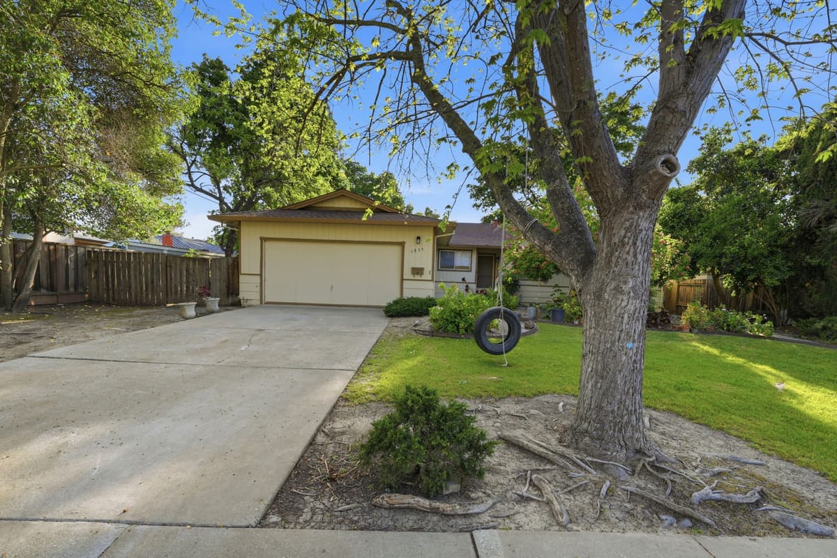 A single-story home with a mature oak tree out front, professionally managed by Bay Vista PM.