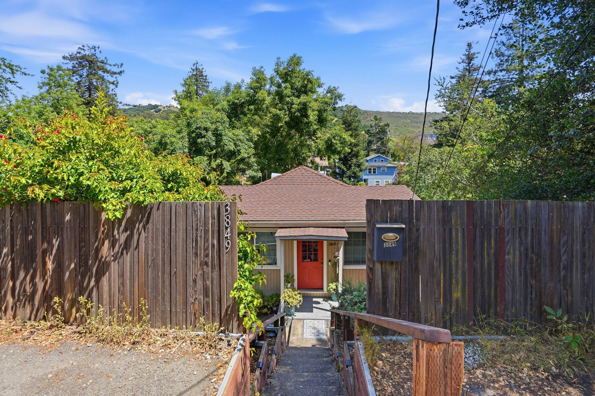 A Bay Vista–managed cottage with a red front door, tucked behind a wooden fence.